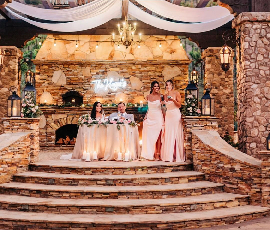 Bridesmaids giving a toast beside the sweetheart table at a stone and timber reception