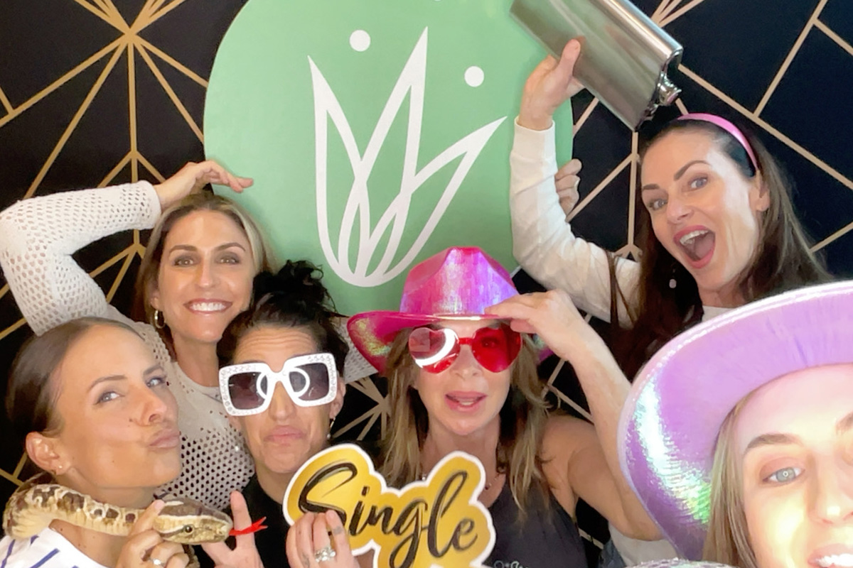 Guests crowding into the photo booth with props and oversized sunglasses